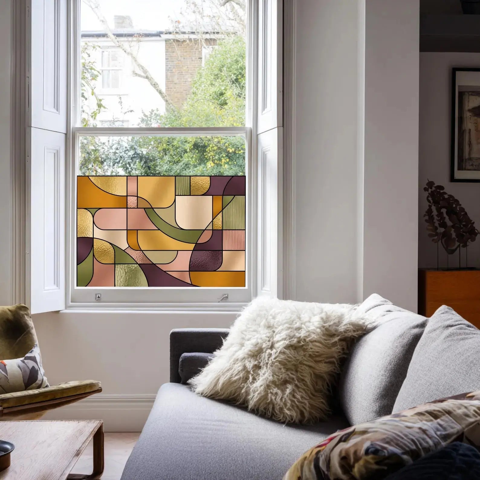 Contemporary stained glass privacy window film in warm amber, olive green and blush tones installed on a sash window.
